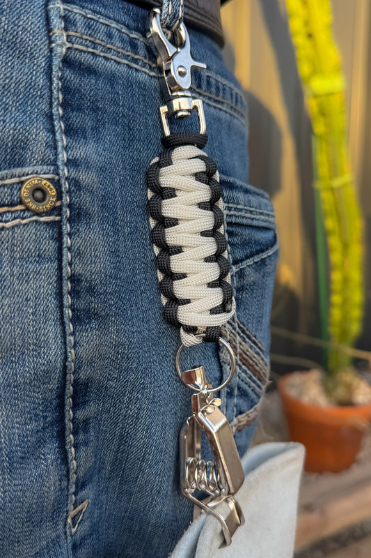 OLTX Black & Bone paracord glove clip in black / cream attached to a belt loop